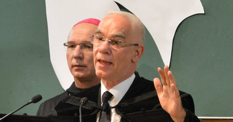 Balog Zoltán istentiszteletet tart zöldes háttér előtt, mögötte egy katolikus püspök áll lila fejfedővel